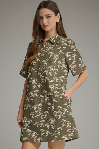A woman modeling a short-sleeve collared shirt dress with an olive green and beige floral stallion print pattern.