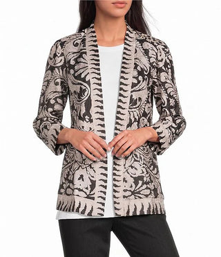 A woman wearing a black and beige patterned open-front cardigan over a white top and black pants.