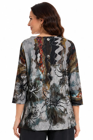 A woman shown from the back wearing a three-quarter sleeve top with a complex abstract floral and watercolor print in black, gray, white, brown, and red tones with decorative buttons down the back.