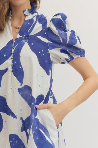 Closeup of woman wearing a blue and white floral eyelet lace dress with her hand in a side pocket