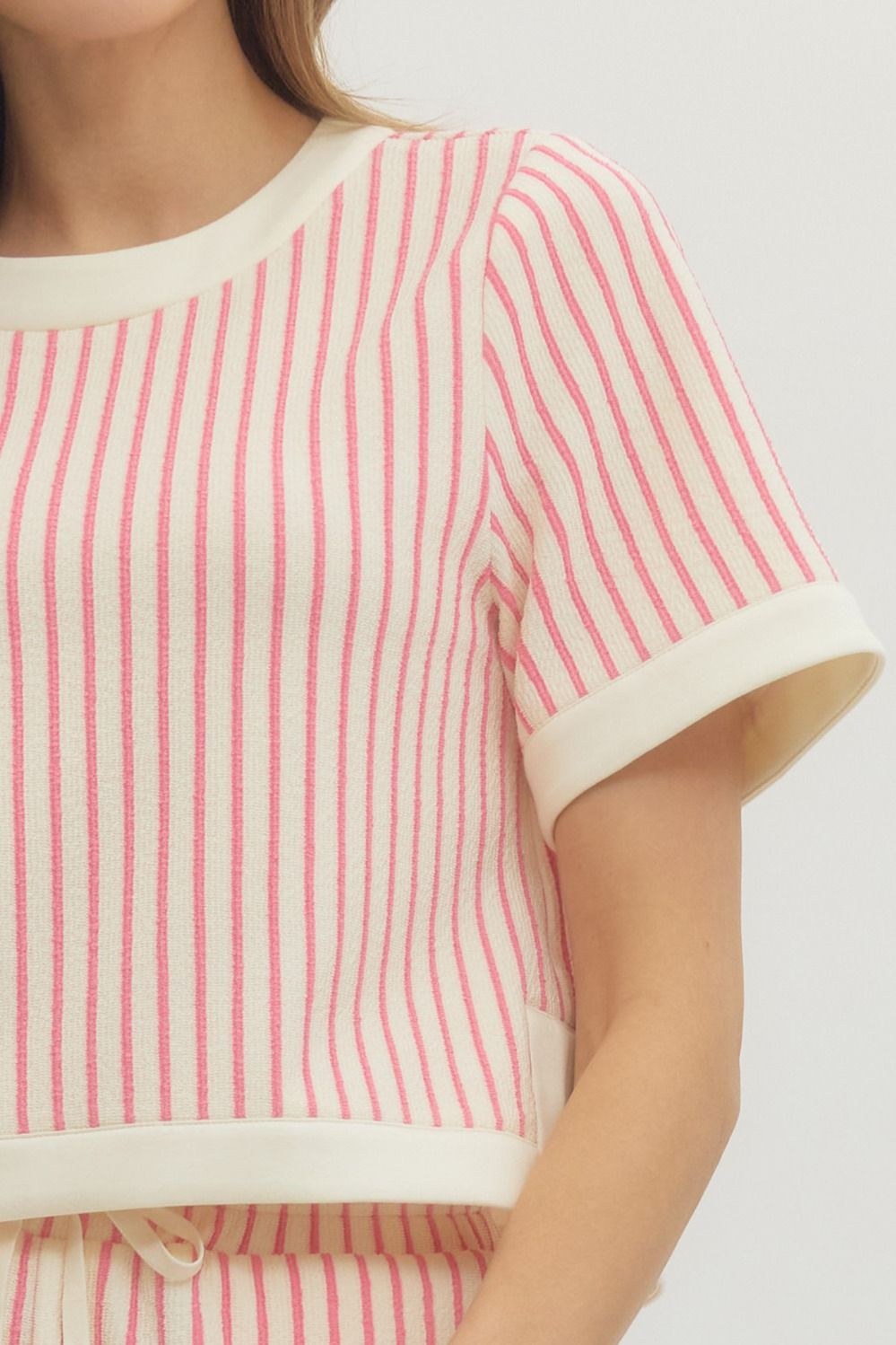 Close-up of a person wearing a light pink and white striped shirt