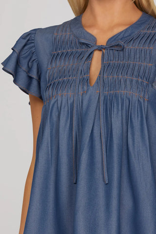 Blue denim top from She & Sky closeup with ruffled sleeves and a tie at neckline 