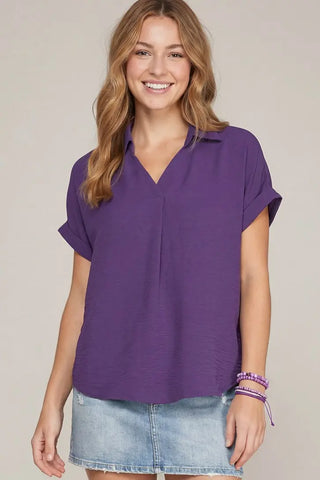 Woman wearing a purple She & Sky collared v-neck shirt and denim skirt 