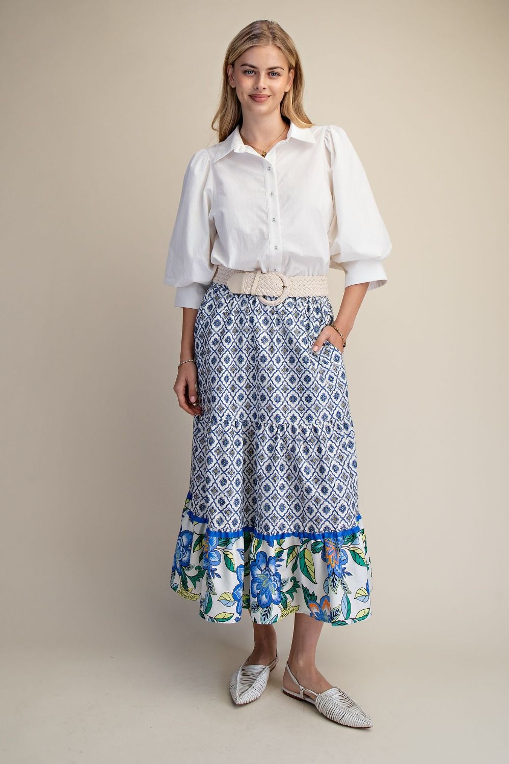 Woman wearing a white Easel blouse and patterned skirt on a beige background