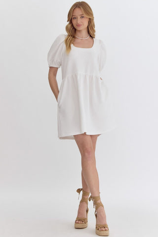 Woman wearing an Entro textured fabric white mini dress on a plain background