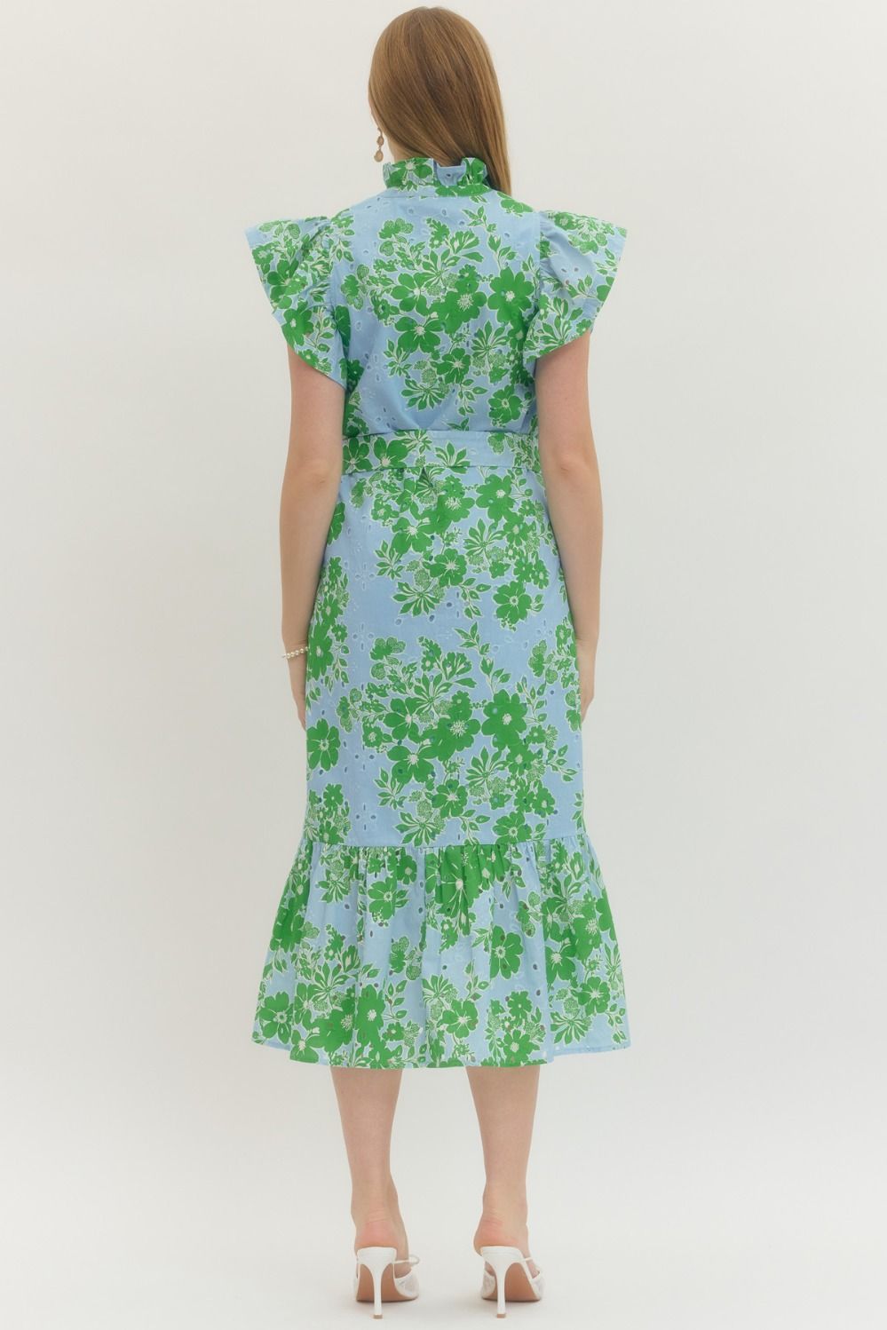 Woman wearing a floral dress with green and blue pattern on a white background