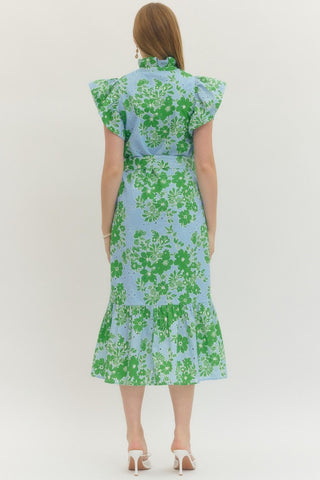 Woman wearing a floral dress with green and blue pattern on a white background