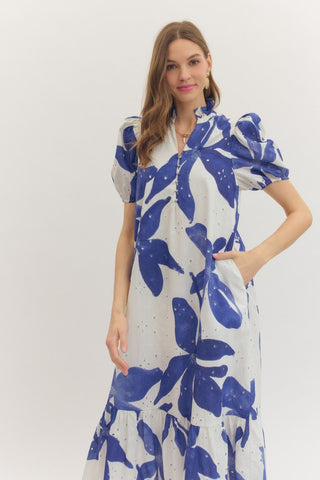 Woman with her hand in a side pocket wearing an Entro white and blue floral midi dress