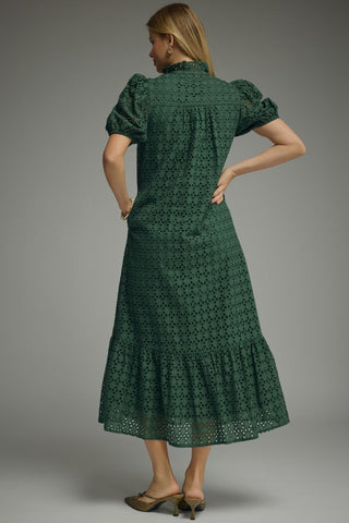 Woman wearing a green dress with puff sleeves against a gray background