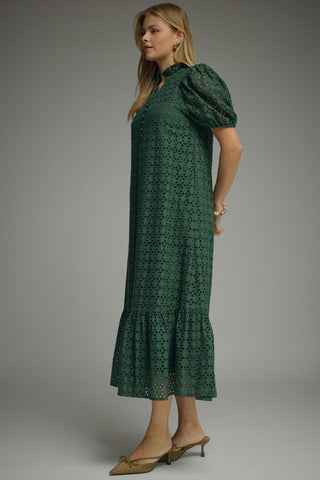 A woman modeling a dark green eyelet midi dress with puff sleeves and a tiered hem from Entro.