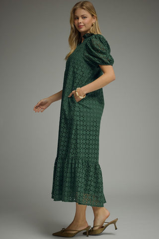 Woman wearing a dark green lace midi dress with side pockets 