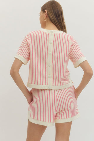 Woman wearing an Entro pink and white striped outfit that the top buttons up the back