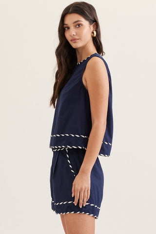 Woman wearing an Entro boutique brand linen blend shorts and sleeveless top with white ribbon trim side view