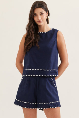 Woman wearing a navy blue romper with white trim on a light background