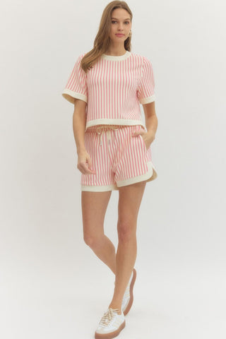 Woman wearing an Entro light pink and white striped outfit on a plain background