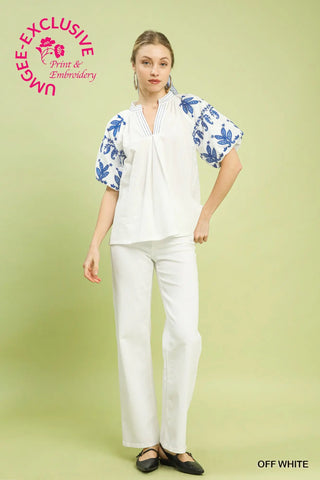 Woman wearing a white outfit with blue floral embroidery on a light green background
