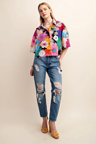 Woman wearing a colorful floral shirt and ripped jeans on a beige background