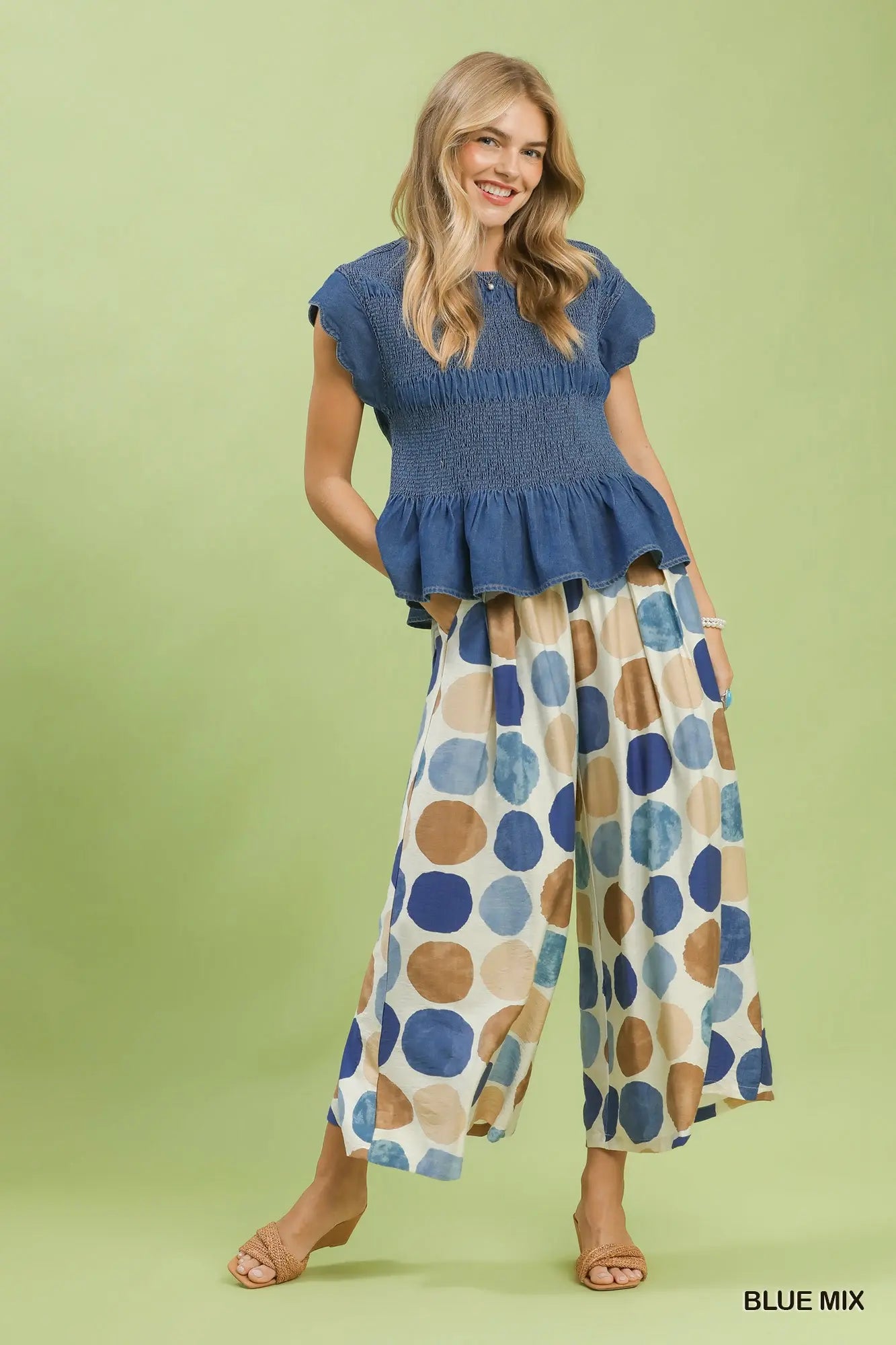 Full view of woman wearing a blue top and patterned dot wide leg pants by Umgee