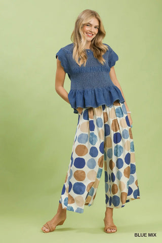 Full view of woman wearing a blue top and patterned dot wide leg pants by Umgee