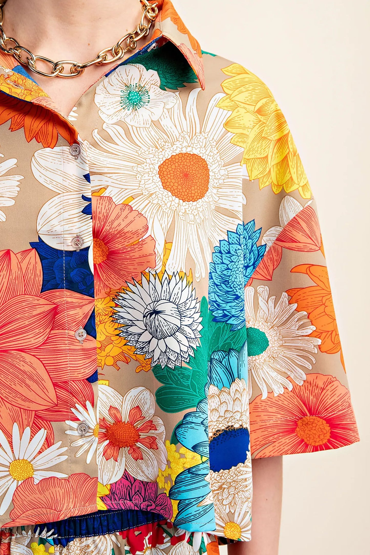 Colorful floral Gigio cropped top closeup with a beige background