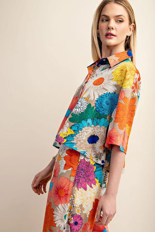 Woman wearing a colorful floral cropped top against a beige background