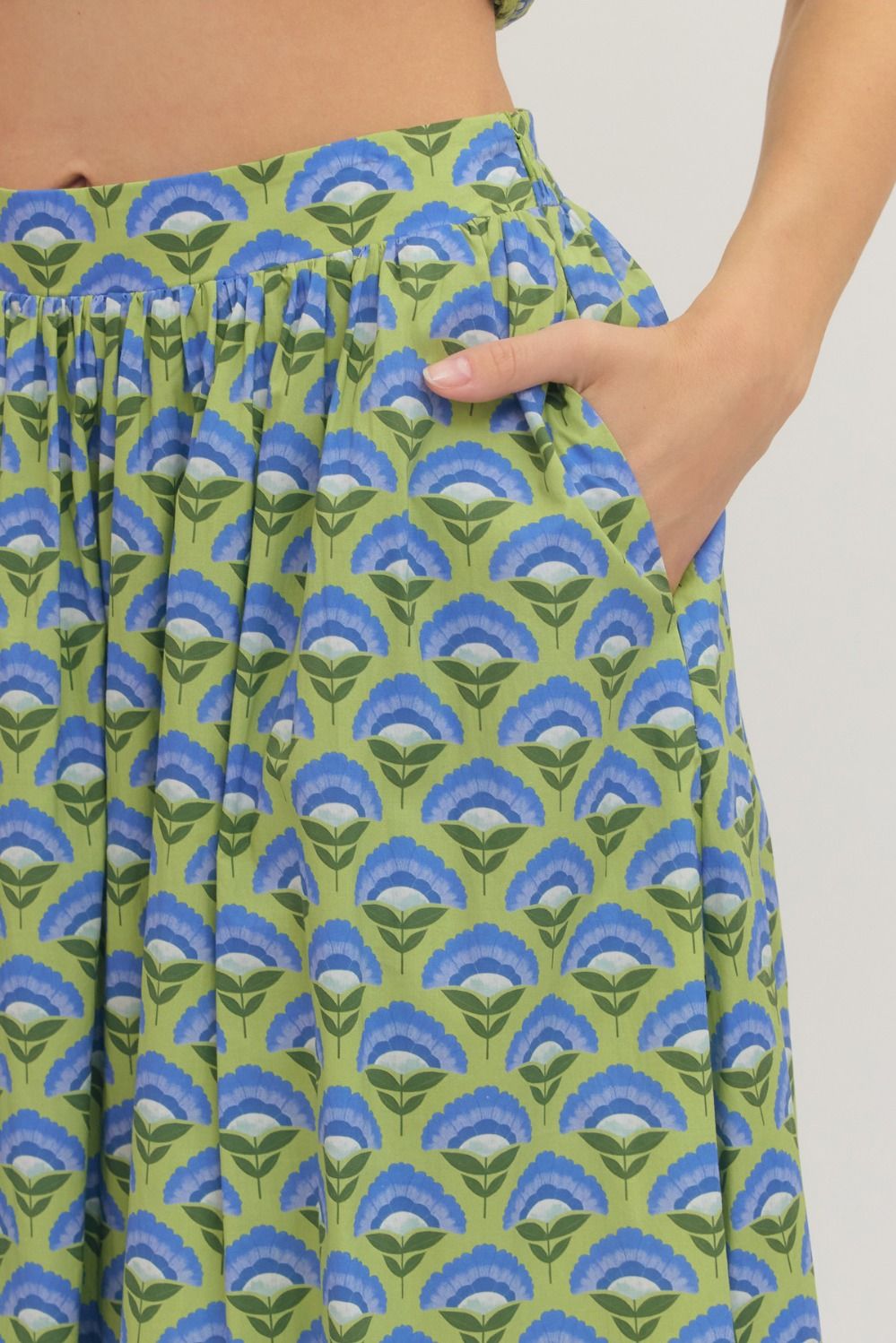 Green and blue patterned Entro skirt closeup view with hand in side pocket