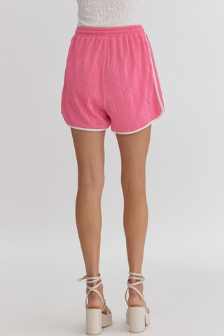 Person wearing pink textured shorts with white trim by Entro rear view