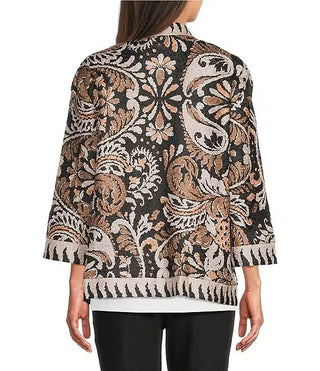 A woman shown from the back wearing a black cropped jacket with a detailed beige and brown paisley pattern, paired with black pants.