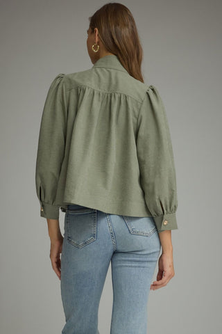 A woman shown from the back wearing an Entro olive green cropped blouse with puffed long sleeves and light blue jeans, photographed against a plain gray studio background.