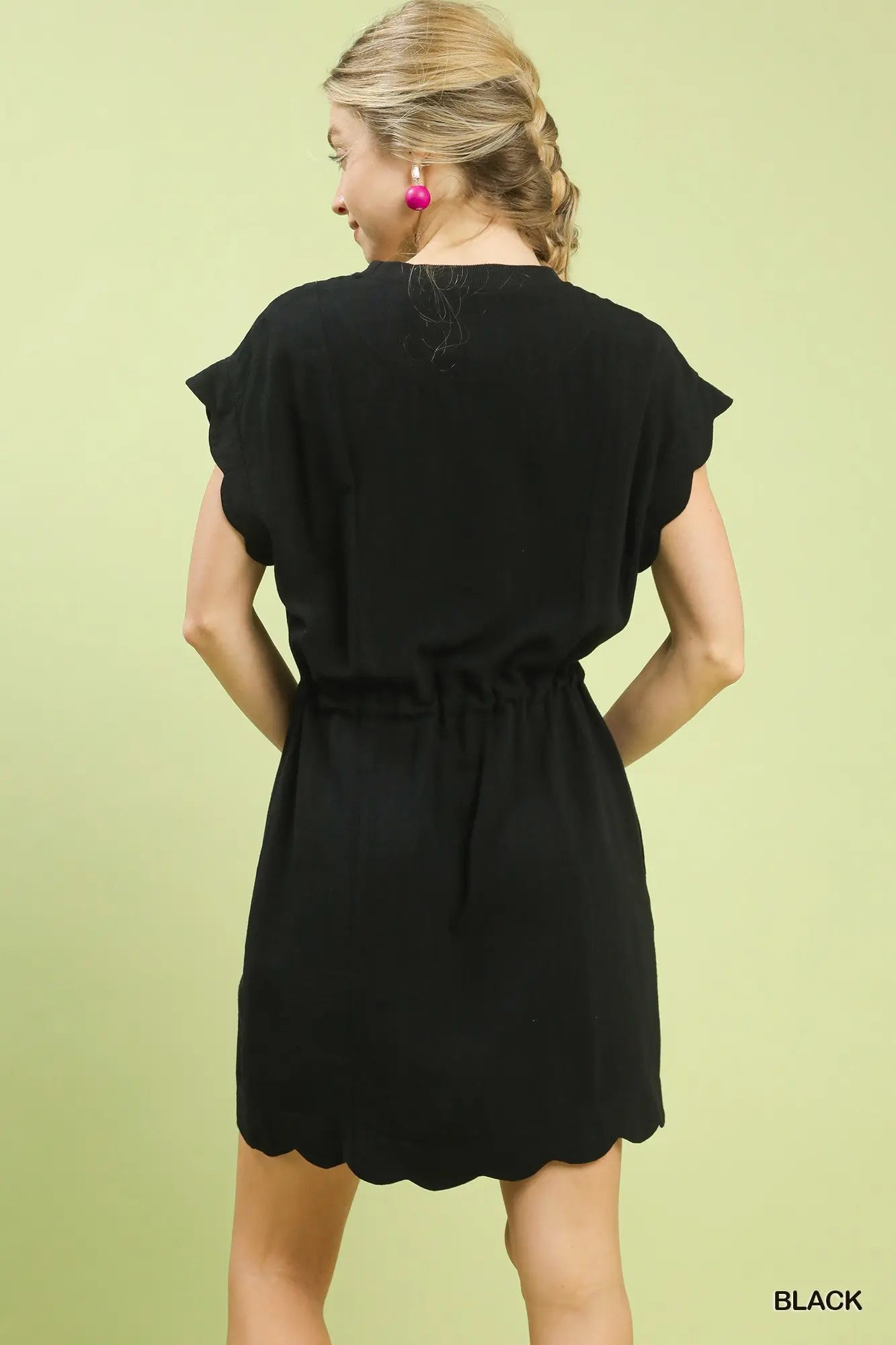 Woman wearing a black dress against a light green background