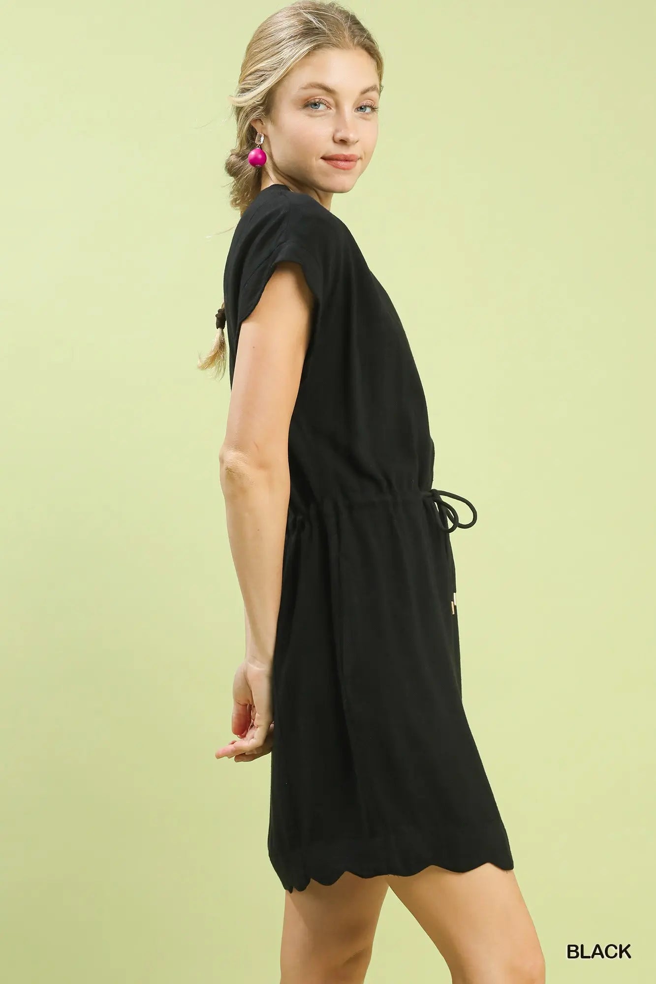 Woman wearing a black dress against a light green background