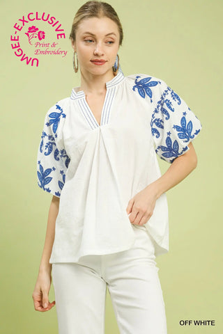 Woman wearing a white blouse with blue floral patterns on a light green background