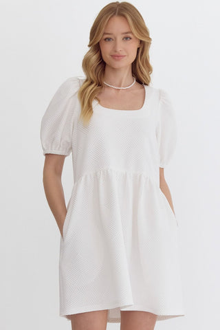 Woman wearing an Entro white mini dress with puff sleeves women boutique